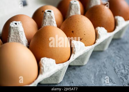 Gepunktete braune Eier liegen in einem Papierbeutel auf einem grauen Betontisch Stockfoto