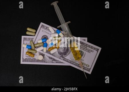 Medikamentenspritze und Geldnote auf schwarzem Hintergrund, teures Behandlungskonzept Stockfoto