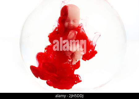 Abtreibungskonzept. Babypuppe im roten Blut sieht aus wie eine Abtreibung. Stockfoto