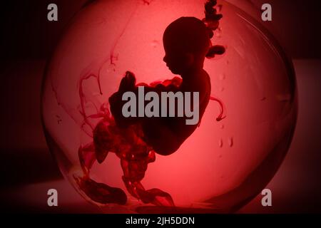 Abtreibungskonzept. Babypuppe im roten Blut sieht aus wie eine Abtreibung. Stockfoto