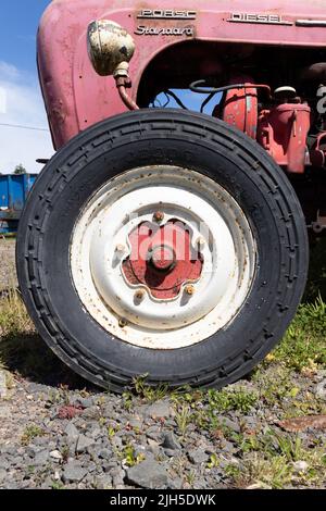 Vorderrad eines unrestaurierten roten Porsche Diesel Standard Traktors Stockfoto