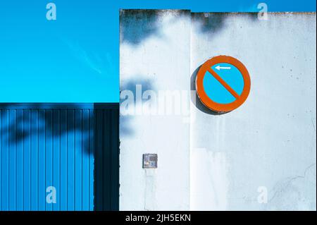 Ein rot-blaues No Parking Schild an einer weißen Wand in Spanien mit leuchtendem Blau und Rot Stockfoto