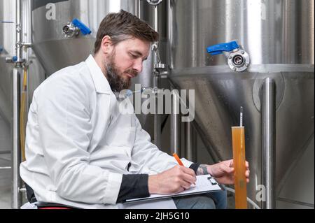 Bierbrauer misst pH-Wert in Bier mit digitalem Messgerät. Hochwertige Fotografie. Stockfoto