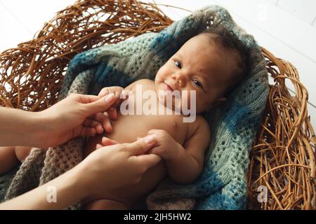 Niedliches neugeborenes Baby, das die Hände der Mutter in der Wiege hält Stockfoto