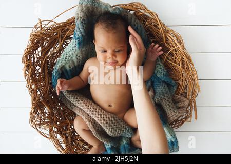 Draufsicht auf Biracial Baby in Weidenwiege Stockfoto
