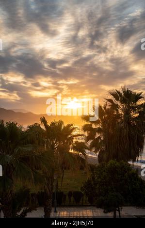 Sonnenaufgang über Meerwasser und Palmen in Torrox Costa, Costa del Sol, kleiner touristischer Ort zwischen Malaga und Nerja, Andalusien, Spanien Stockfoto