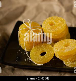 Zitronen-, Orangen- und Grapefruitscheiben in Zucker isoliert auf einem hölzernen Hintergrund, Nahaufnahme. Marmelade Süßigkeiten. Süßigkeiten mit Zitrusgeschmack. Süßigkeiten Stockfoto