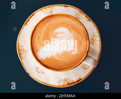 Draufsicht auf eine Tasse Cappuccino-Kaffee in Nahaufnahme auf einem dunklen Hintergrund Stockfoto