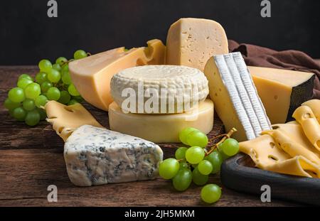 Verschiedene Käsesorten und frische Trauben auf Holzboden. Stockfoto