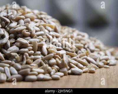 Ein Haufen geschälter Sonnenblumenkerne auf einer Holzoberfläche, Nahaufnahme. Samen ohne Schale. Stockfoto