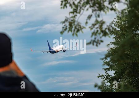 Rückansicht eines Passagierflugzeugs, das am blauen Himmel vor dem Hintergrund von Bäumen abheben soll Stockfoto