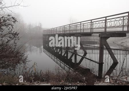 Ufer des Flusses und Damm im Nebel Stockfoto