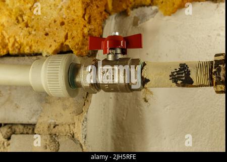 Wasserhahn am Heizrohr zwischen Eisenrohr und Kunststoffrohr. Heizung Wohnung im Winter. Stockfoto