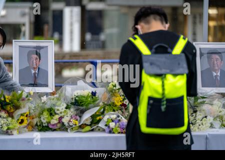 Tokio, Japan . 15.. Juli 2022. 15. Juli 2022. Seit dem Tod des ehemaligen Premierministers Shinzo Abe ist eine Woche vergangen. Im Hauptquartier der LDP in Tokio wurden auf dem Parkplatz ein Tisch mit Bucheinstieg und ein Blumenanbietstand aufgestellt, und Menschen kamen, um nacheinander um den ehemaligen Premierminister zu trauern. Während des gelegentlichen heftigen Regens am Freitag boten viele Menschen Blumen und Gebet an. Die Linie zum Tisch erstreckte sich mehrere hundert Meter vom Parteihauptsitz bis zur Nationaldiätebibliothek, und Menschen jeden Alters standen an der Reihe. (Foto: Mihoko Owada/Sipa USA) Quelle: SIPA USA/Alamy Live News Cr Stockfoto