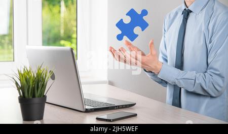 Geschäftsmann hält ein Puzzleteil in seinen Händen.das Konzept der Zusammenarbeit, Teamarbeit, Hilfe und Unterstützung im Geschäft Stockfoto