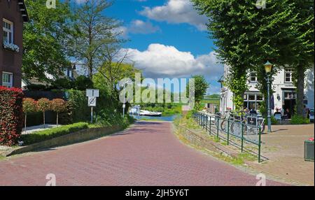 Venlo (Steyl), Niederlande - Juli 9. 2022: Rote gepflasterte Straße im holländischen Dorf zur Fährstation am Fluss Maas Stockfoto