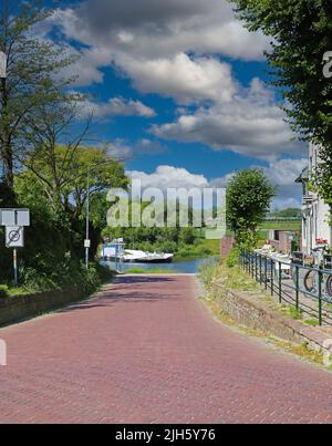 Venlo (Steyl), Niederlande - Juli 9. 2022: Rote gepflasterte Straße im holländischen Dorf zur Fährstation am Fluss Maas Stockfoto