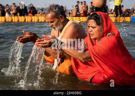Hindu-Gläubige beten und baden im heiligen Ganges-Fluss bei Sonnenaufgang beim Kumbh Mela Festival in Allahabad (Prayagraj), Uttar Pradesh, Indien. Stockfoto