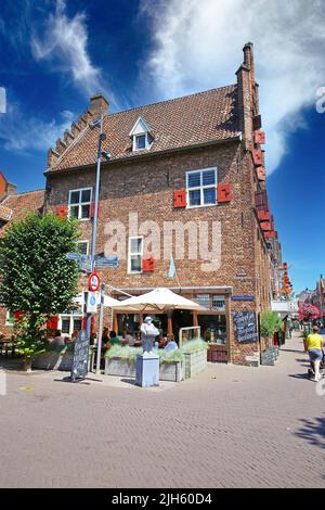 Venlo (Romerhuis), Niederlande - Juli 9. 2022: Schöner Platz mit mittelalterlichem Backsteinhaus Straßencafé, Leute sitzen außen, blauer Sommerhimmel Stockfoto