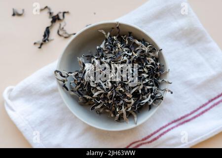 Getrocknete mun-Pilze, traditionelle chinesische Medizin und Küche. Pilze Zutaten in Teller auf beigem Hintergrund Stockfoto