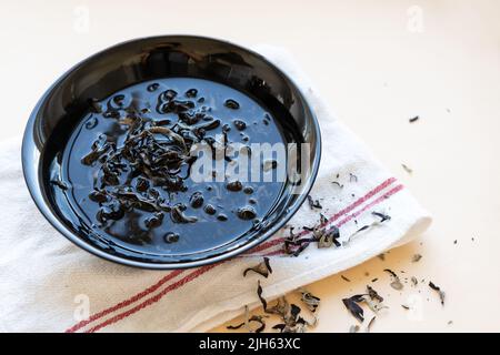 Getrocknete mun-Pilze, traditionelle chinesische Medizin und Küche. Pilze Zutaten in Teller auf beigem Hintergrund Stockfoto