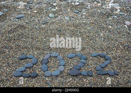 Jahr 2022 aus schwarzen Steinen am Sandstrand. Stockfoto