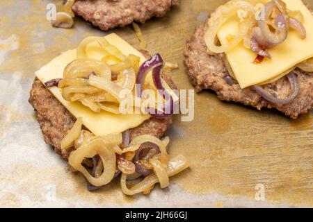 Gebratener Burger mit Käse und gebratenen Zwiebeln. Rostiger Hintergrund. Draufsicht. Stockfoto