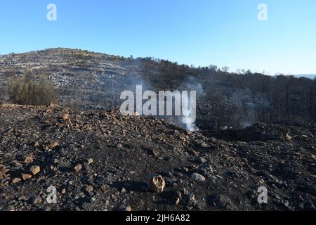 Die verbrannte Deponie ist nach dem Brand, der vor zwei Tagen im Dorf Raslina in der Nähe von Vride, Kroatien, am 14. Juli 2022 ausbrach, zu sehen. Am Mittwoch, dem 13. Juli 2022, brachen in Dalmatien drei Brände aus - zwei in der Gespanschaft Sibenik-Knin und eines in der Gespanschaft Zadar. Viele Einheimische wurden evakuiert und über 300 Feuerwehrmänner und 50 Armeeangriffe setzen mit Unterstützung von drei Canadair-Löschflugzeugen und zwei Lufttraktoren ein Waldfeuer. Die Situation ist heute ruhiger und das Feuer breitet sich nicht mehr außer Kontrolle aus. Kredit: Pixsell Foto & Video Agentur/Alamy Live Nachrichten Stockfoto