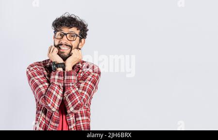 Gutaussehender Mann in einer Brille, freundlich lächelnd, Nahaufnahme eines lächelnden Mannes, der auf isoliertem Hintergrund seine Wangen berührt, Gesicht eines lächelnden freundlichen Mannes mit Händen Stockfoto