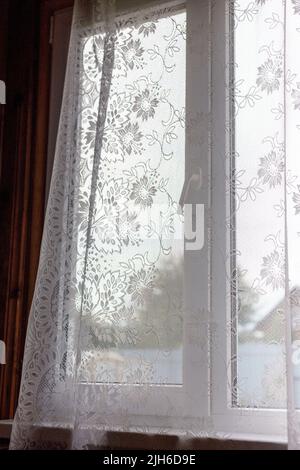 Fenster mit offenen Vorhängen. Transparente Vorhänge mit Mustern. Stockfoto