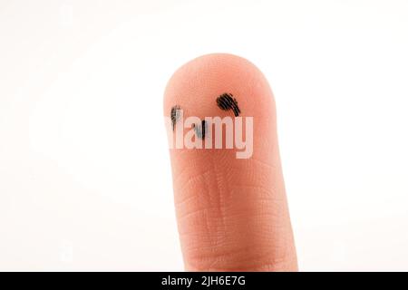 Schwarze Punkte, die ein Gesicht auf der Fingerspitze bilden Stockfoto