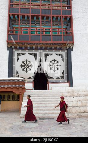 Zwei Novizen gehen über den Klosterhof, das Eingangsportal auf der Rückseite, Hemis Gompa, Hemis, Ladakh, Indien Stockfoto