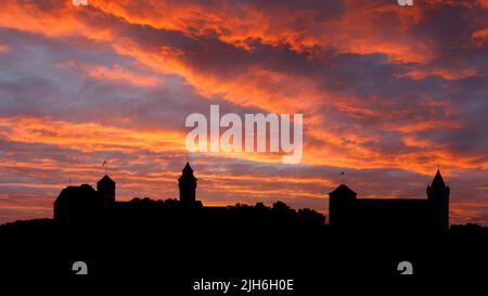 Feuerroter Abendhimmel nach Sonnenuntergang mit Skyline, Silhouette von links Kaiserburg mit Heidenturm und Sinwellturm, rechts ehemalige Kaiserstallung mit Stockfoto