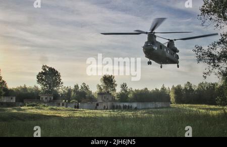 Ein Hubschrauber der Nationalgarde der New York Army CH-47, der dem Bataillon der B Company 3., 126. Aviation Regiment, zugewiesen wurde, landet während einer Übung in Fort Drum, Juni 30, auf einem Trainingsbereich. Während der Übung besetzten und verteidigten Soldaten des Bataillons 1., des Infanterie-Regiments 69., der Nationalgarde der New Yorker Armee eine Position gegen eine feindliche Kraft. Das 69. Regiment führt in Fort Drum eine Vormobilisierungsschulung durch, um einen bevorstehenden Einsatz am Horn von Afrika vorzubereiten. (USA Foto der Armee von Staff Sgt. Alexander Rektor) Stockfoto