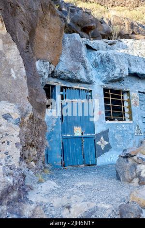 Verlassene Höhlenhaus mit einer blauen Holztür in der Nähe von Lol Llanos, La Palma, Kanarische Inseln. Rustikaler, alter, kaputter und gealterter Eingang zu einem leerstehenden Haus Stockfoto