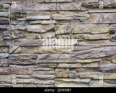 Steinfliesen. Fassadenverkleidung des Hauses. Mauerwerk. Braune Wand Stockfoto