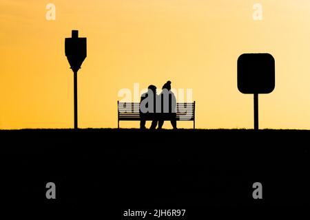 Paar sitzt auf einer Bank in Liebe Silhouette Stockfoto
