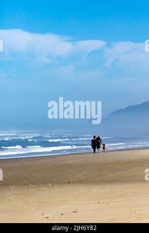 Heceta Beach, Florence, Oregon, August 23, 2019: Menschen und ein Hund gehen am Strand. Vertikal Stockfoto