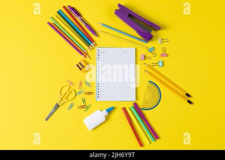Stellen Sie sich verschiedene Büromaterialien und Plastikutensilien, Notizbücher, Buntstifte auf gelbem Hintergrund vor Stockfoto