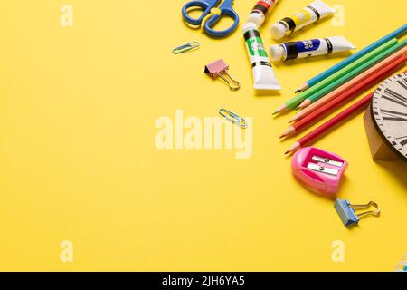 Stellen Sie sich verschiedene Büromaterialien und Plastikutensilien, Farben, Buntstifte auf gelbem Hintergrund vor Stockfoto