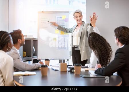 Dank all Ihrer Bemühungen waren Sie auf dem richtigen Weg. Eine Geschäftsfrau gab ihrem Kollegen während eines Meetings in einem Büro eine hohe Fünftel. Stockfoto