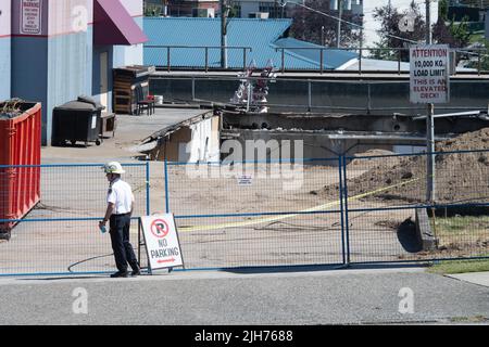 14. Juli 2022, Vancouver, British Columbia, Kanada: Ein Feuerwehrbeamter in Vancouver, B.C. schließt den Standort, an dem am 14. Juli ein Dachparkldeck auf einen Bürobereich darunter einstürzte. Rettungsmannschaften arbeiteten mehr als 36 Stunden auf der Suche nach einer Person, die als vermisst gemeldet wurde, und die von der Familie in den lokalen Medien als Ben Sotelo identifiziert wurde. Gegen 10:30 Uhr am nächsten Tag sagte die Polizei, dass ein Leichnam von der Anlage geborgen wurde. Nach Angaben der Feuerwehr stürzte das Deck unter dem Gewicht eines Laders ein und schuf ein Loch in einer Höhe von neun mal 12 Metern. Acht Personen, darunter der Fahrer des Laders, wurden aus dem Gebäude gerettet. (Bild: Stockfoto