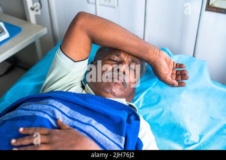 Älterer älterer Mann, der an Schlaflosigkeit leidet, während er ins Krankenhaus eingeliefert wurde - Konzept von psychischen Erkrankungen, Krankheiten und Einsamkeit. Stockfoto