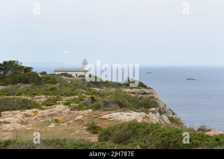 Leuchtturm am Far de Cap Blanc auf Mallorca, Spanien. Marineschiffe auf See im Hintergrund Stockfoto