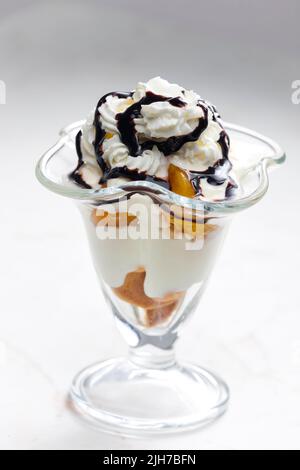 Eis mit geschmorten Pfirsich und Schlagsahne Stockfoto