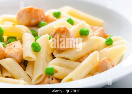 Pasta Penne mit Lachs und grünen Erbsen Stockfoto