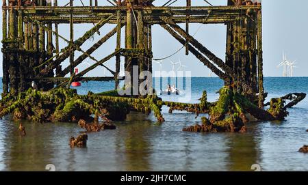 Brighton UK 16. July 2022 - Paddler am frühen Morgen erhalten an einem schönen sonnigen Morgen bei Ebbe eine ungewöhnliche Aussicht auf den West Pier von Brighton, da für den frühen Teil der nächsten Woche eine extreme rote Wetterwarnung ausgegeben wurde : Credit Simon Dack / Alamy Live News Stockfoto