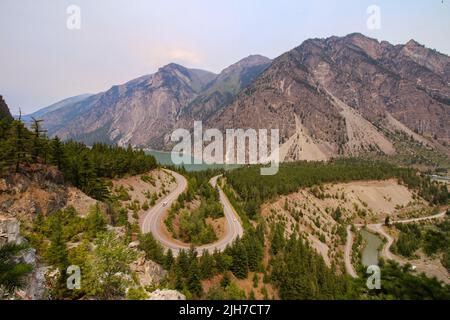 Seton Lake Lookout in Lillooet, B.C. der Blick auf die berühmte U-Kurve, umgeben von wunderschönen Bergen und türkisfarbenem See. Trübe Himmel. Stockfoto