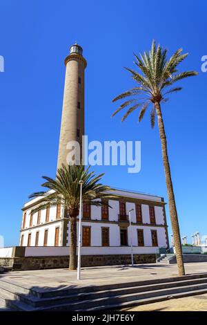 Hoher Leuchtturm über blauem Himmel im Sommer neben großer grüner Palme am Strand von Maspalomas auf den Kanarischen Inseln. spanien Stockfoto