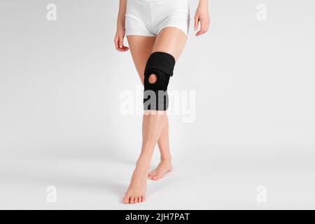 Kniestützenstrebe am Bein isoliert auf weißem Hintergrund. Elastische orthopädische Orthese. Anatomische Hosenträger für Kniefixierung, Verletzungen und Schmerzen. Schutz Stockfoto